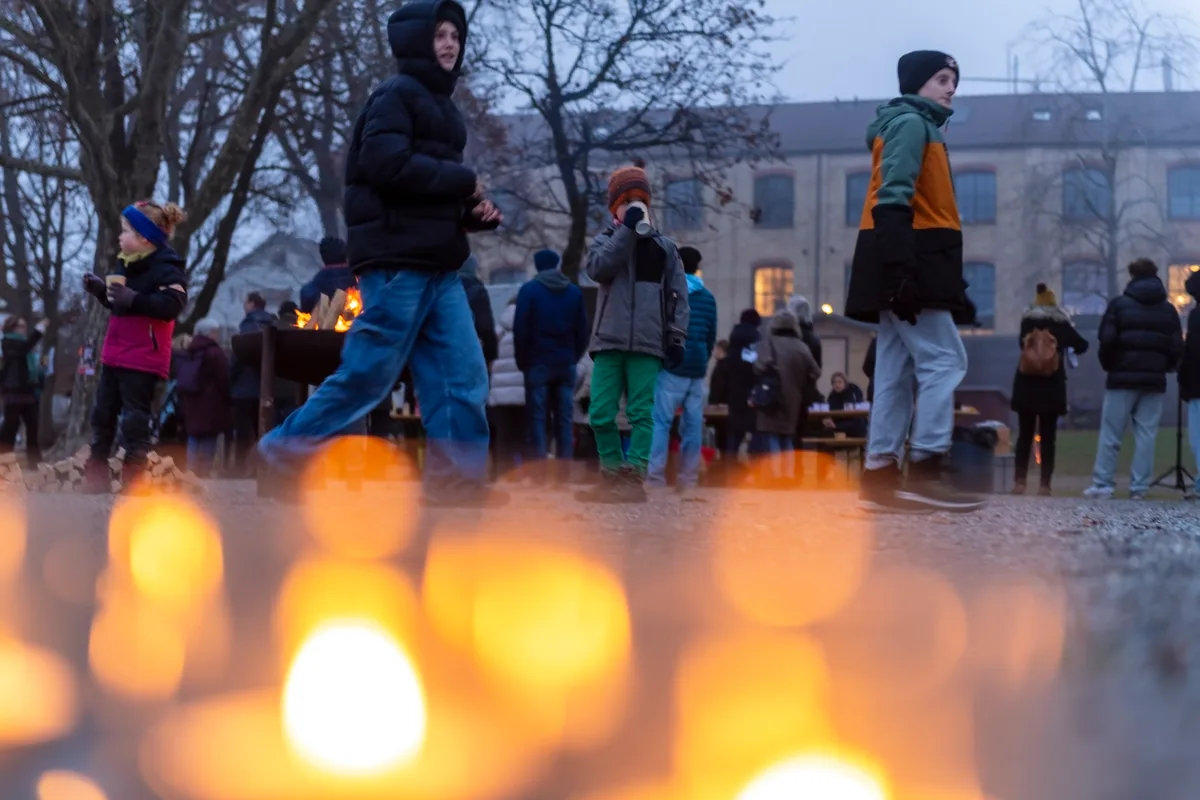 Ein Lichtermeer aus Kerzen, dahinter stehen Menschen und schauen andächtig.
